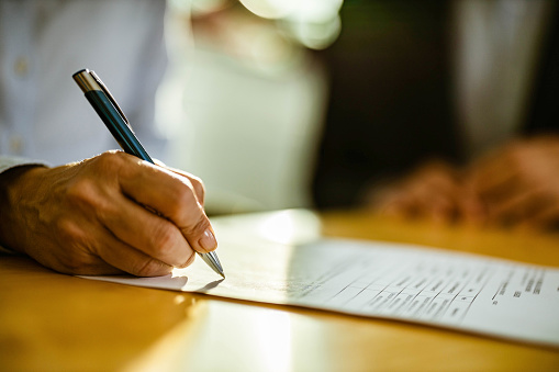 Close up of unrecognizable female person signing a contract. Copy space.